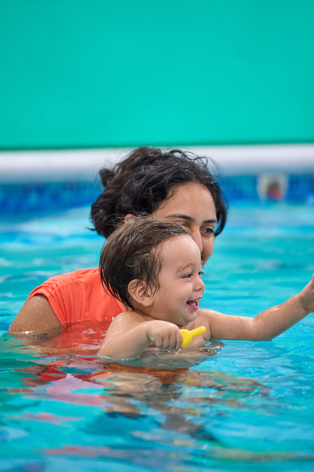 Mamá abrazando a su bebé dentro de la piscina